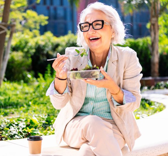 Lady smiles while eating salad