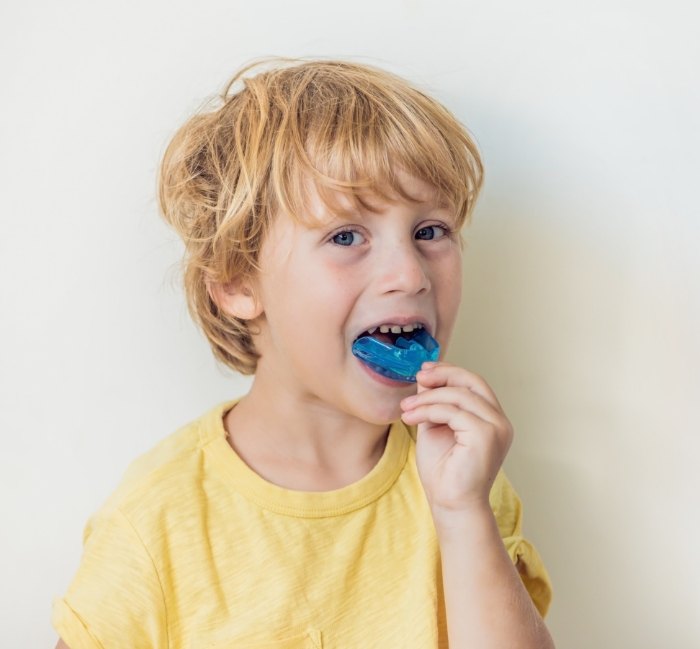 Child placing blue athletic mouthguard