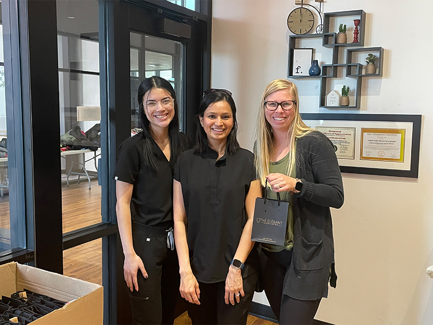 Three women standing in front of awards on wall
