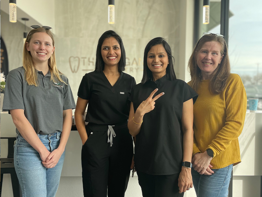 Four women smiling in a row in reception area of dental office