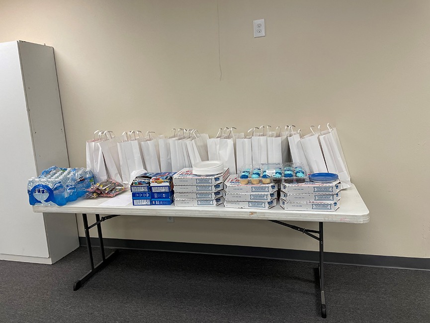 Pizza boxes, cupcakes, and gift bags on a table