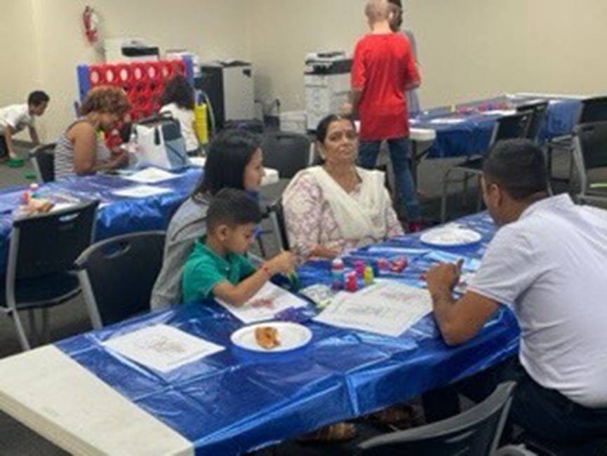 Adults sitting at table and child using paint