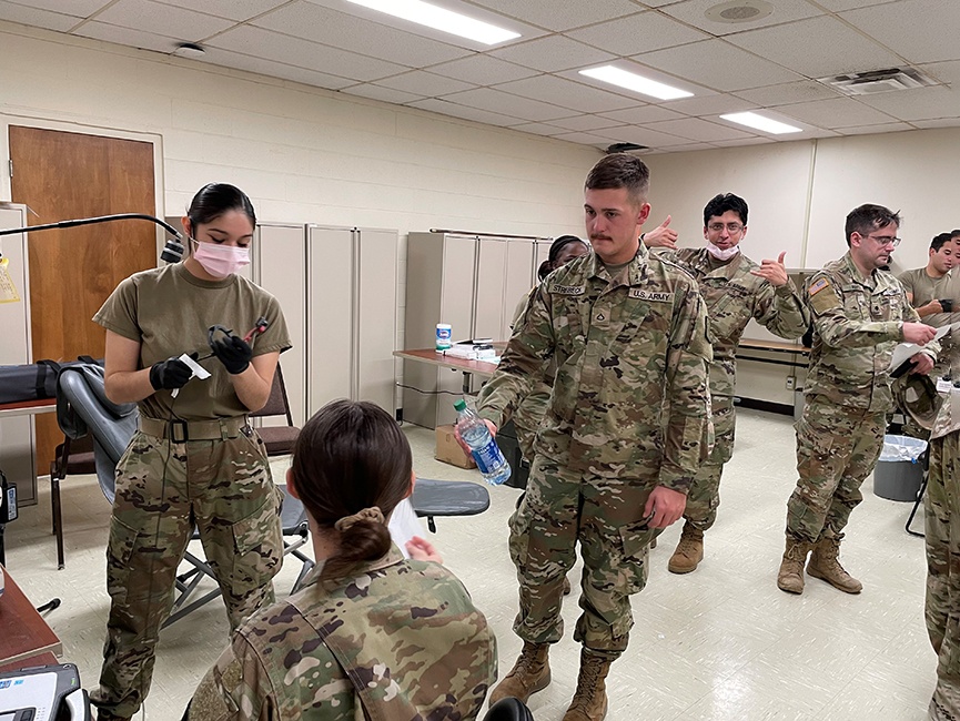 Multiple soldiers with one handing another a water bottle