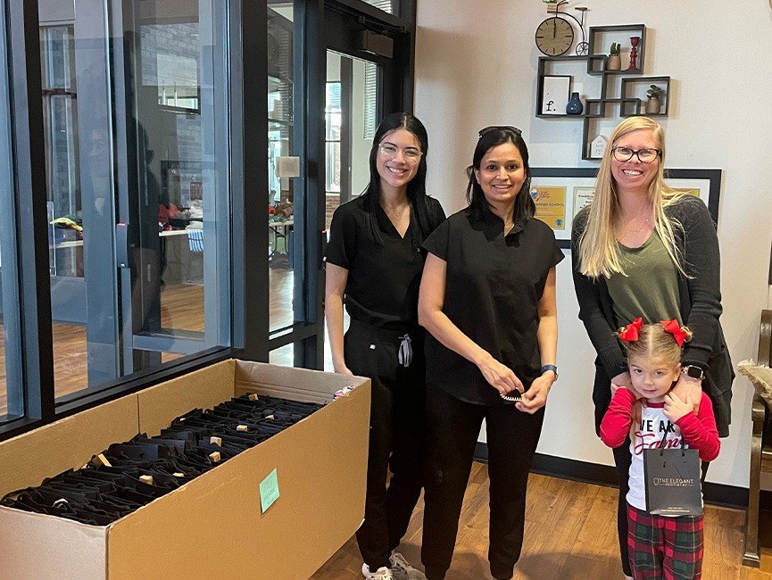 Three women and little girl smiling in dental office