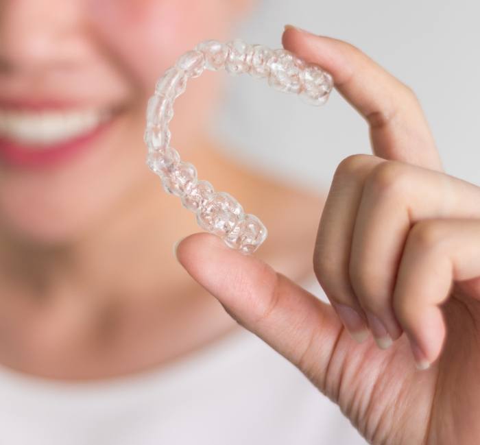 Hand holding Invisalign clear braces tray