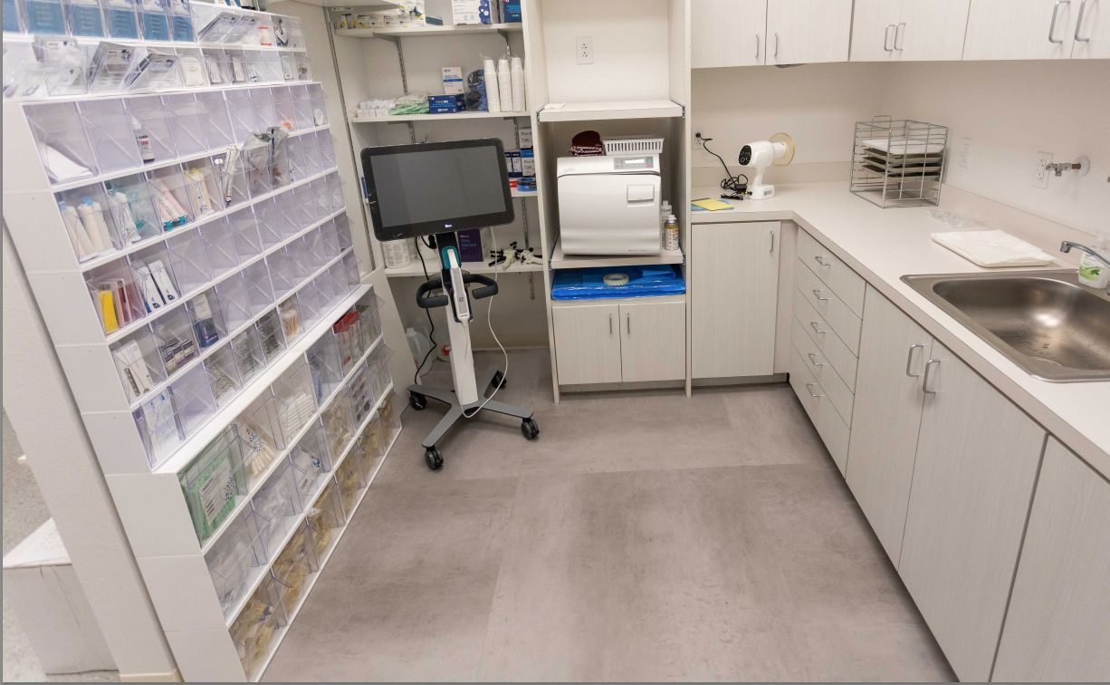 Dental laboratory with full shelves, monitor, and sink