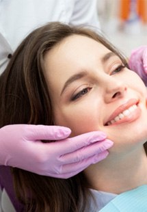 young woman smiling while looking in dental mirror 