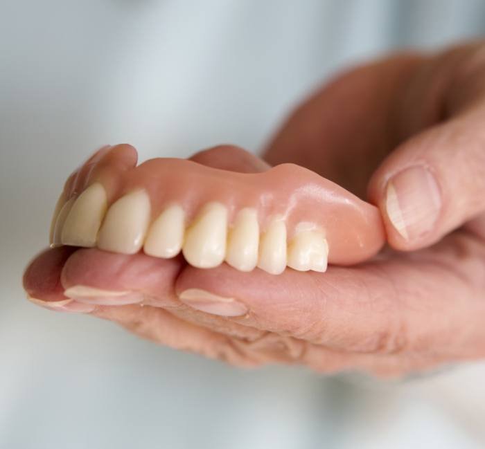 Hand holding full dentures